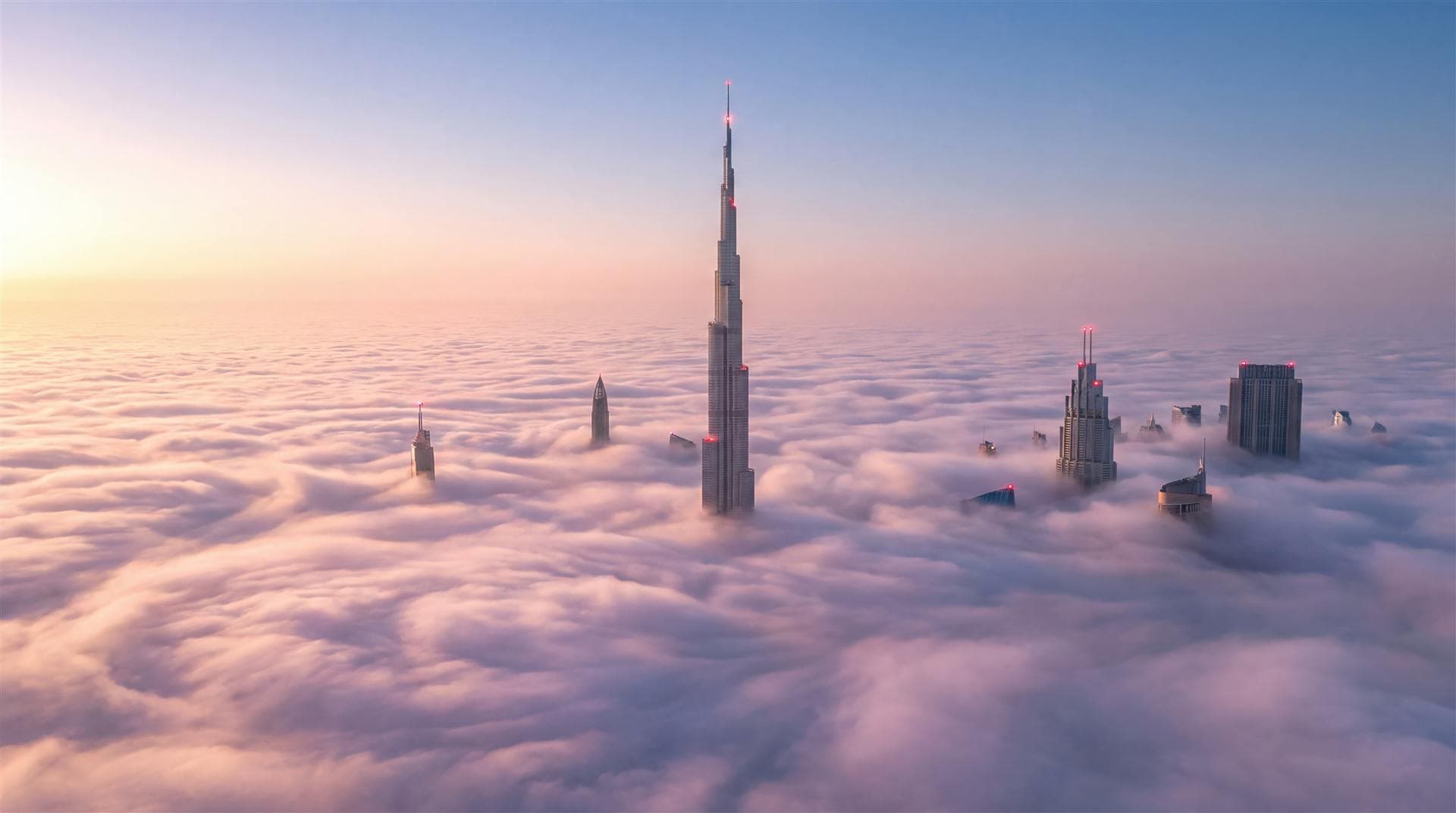 Burj Khalifa and Downtown towers rising above a sea of clouds at sunrise